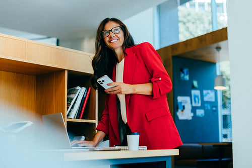 Confident professional woman working in an office with laptop and smartphone