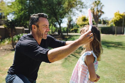 Man putting a rabbit ear headband on her daughter