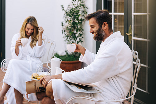 Cheerful married couple having tea in morning robes