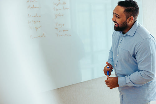 Indian professional discussing ideas with a friendly demeanor at a whiteboard