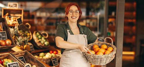 Happy grocery store owner holding a basket of fresh organic fruits