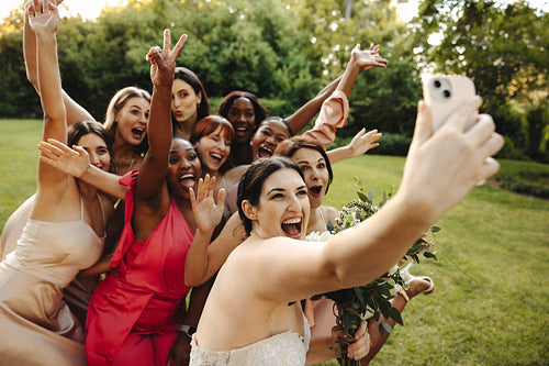 Bride taking a selfie with bridesmaids in outdoor celebration