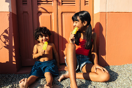 Children enjoying ice pops outside on a warm and sunny day