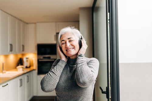 Mature woman enjoying some music on wireless headphones