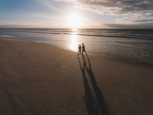 Beautiful beach with couple of runner running on the shore