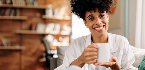 Cheerful young woman having coffee in the morning at home