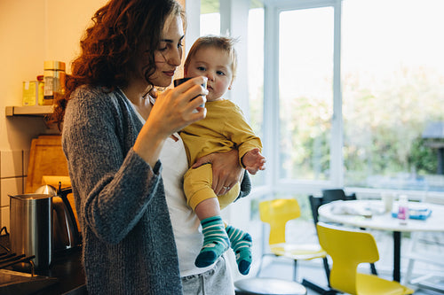 Woman carrying her son and having coffee