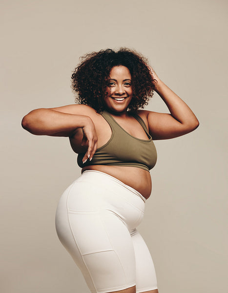 Plus size confidence: Woman smiling as she dances in a studio, wearing sports clothing