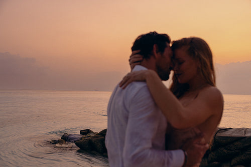 Sunset serenade: Newlyweds embracing passionately at their destination wedding