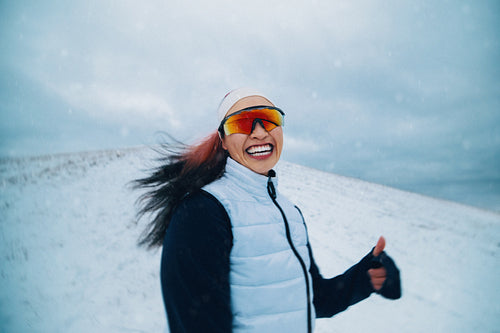 The sport of running takes a woman through winter snow in an outdoor scene