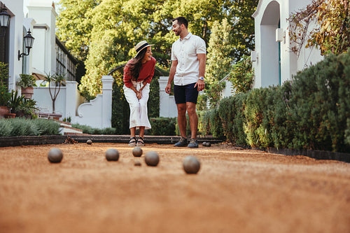 Cheerful young couple playing boules together