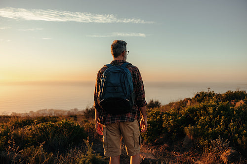 Anonymous backpacker looking at the view on a hilltop