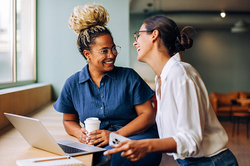 Two women enjoying a cheerful conversation by a laptop