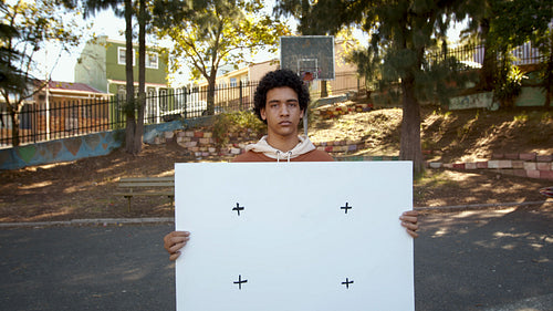 Teenage boy holding a blank banner outside