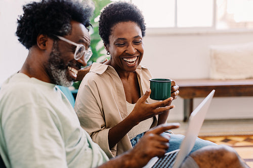 Happy couple enjoying a cozy moment at home, using a laptop together