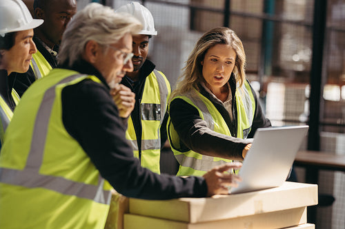 Warehouse employees having a discussion using a laptop