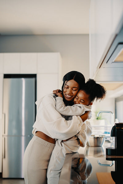 Cute mom and daughter hugging each other in matching outfits