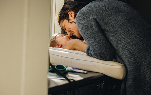 Woman playing with baby lying on changing table