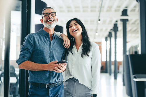 Two happy colleagues smiling while standing together