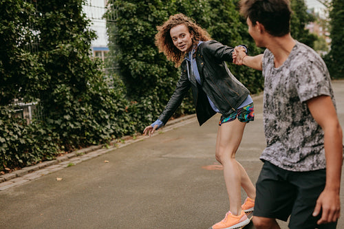 Teenage girl skating on a basketball court with friend
