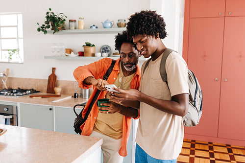 Father and son using a mobile phone together during their morning routine