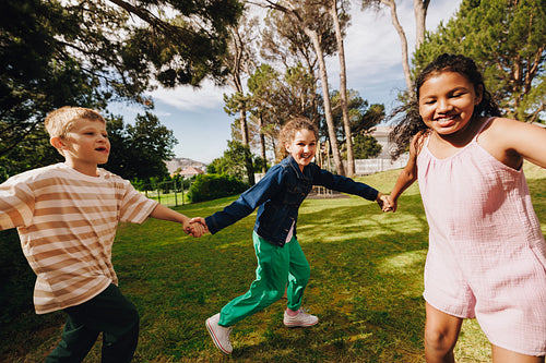Children holding hands and playing together outdoors in a park