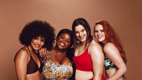 Group of happy different size women in bikinis