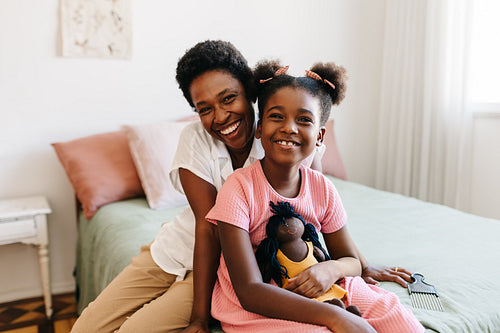 Mother and daughter sharing quality time, smiling together in bedroom