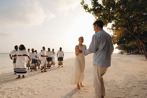 Resort guests dancing on the beach with traditional musicians