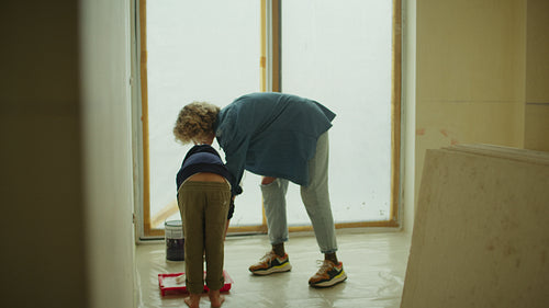 Learning by doing: Mother and son painting wall together