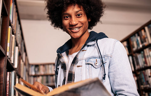 Young black man with book in college library