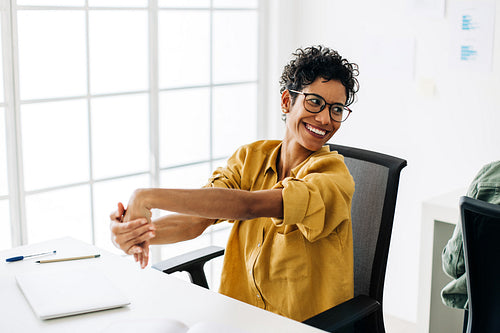 Business woman stretching her hands as she takes a break in the office