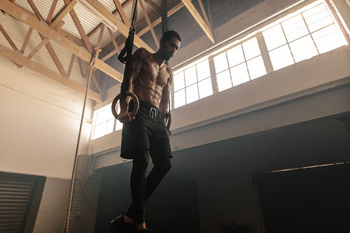 Muscular man exercising on gymnastic rings