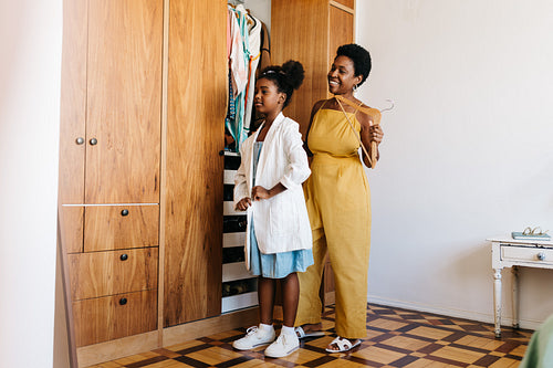 Confident young girl trying on her mom's jacket in front of the mirror