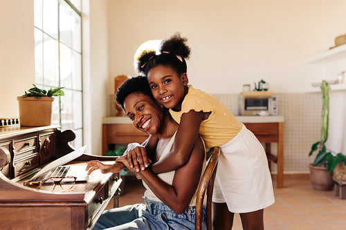 Working mom at home: Mother and daughter embracing happily during work break