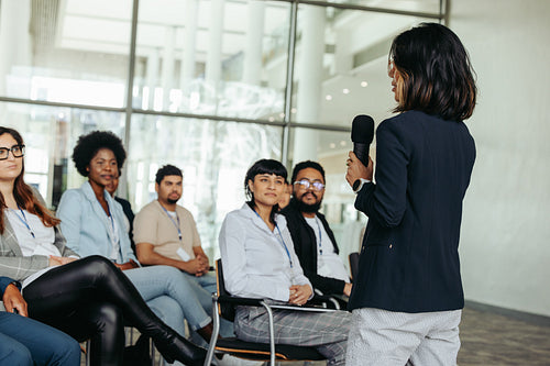 Asian business woman speaker giving a presentation at a conference with an engaged audience