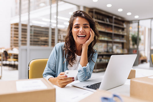 Happy online store manager using a smartphone in a warehouse