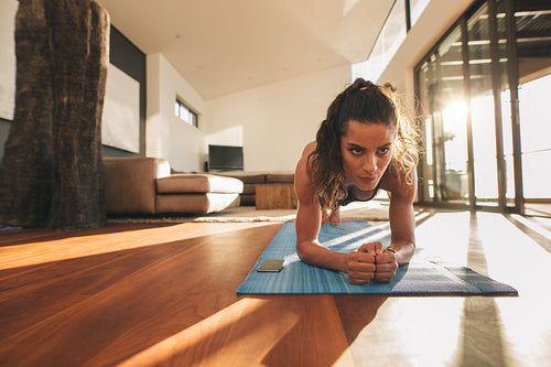 Fit young woman doing push ups at home