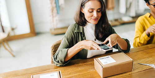 Dropshippping and order fulfilment: Woman scanning a qr code with her smartphone