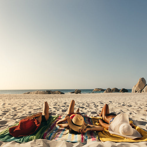 Women relaxing at the beach wearing sun hats