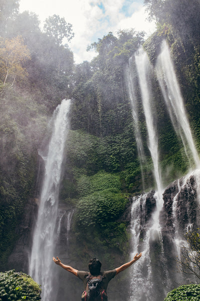 Young man standing by waterfall