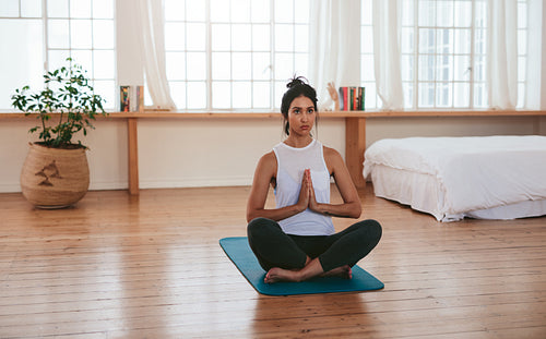 Peaceful young woman meditating at home