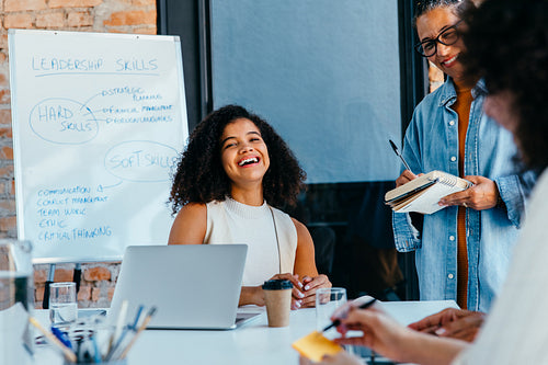 Young professional woman smiling during a collaborative business meeting discussing leadership skills and strategies
