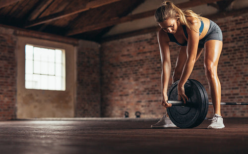 Woman at the gym with heavy weight barbell