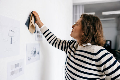 The furniture designer studies material options on a sketch board in the design studio