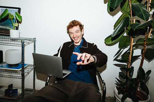 A casual work session shows a young man sitting with a laptop at home.