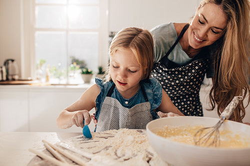 Mother teaching her daughter to cook in kitchen