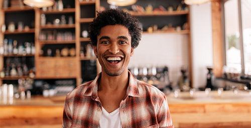 Happy young man laughing in a cafe
