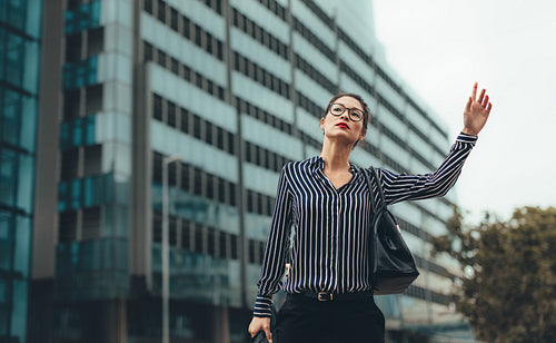 Female business executive hailing taxi