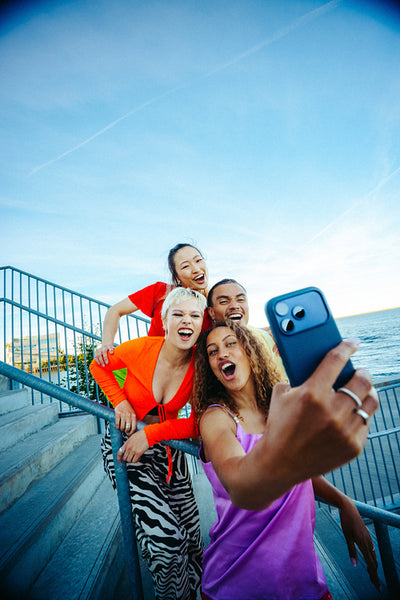 Friends take a selfie with a smartphone on waterfront stairs outdoors